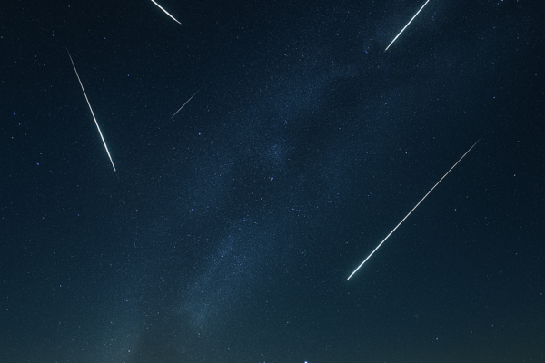 Gecenin qaranliginda sehmada Geminid meteor yagisinin parlaq izleri gorunur